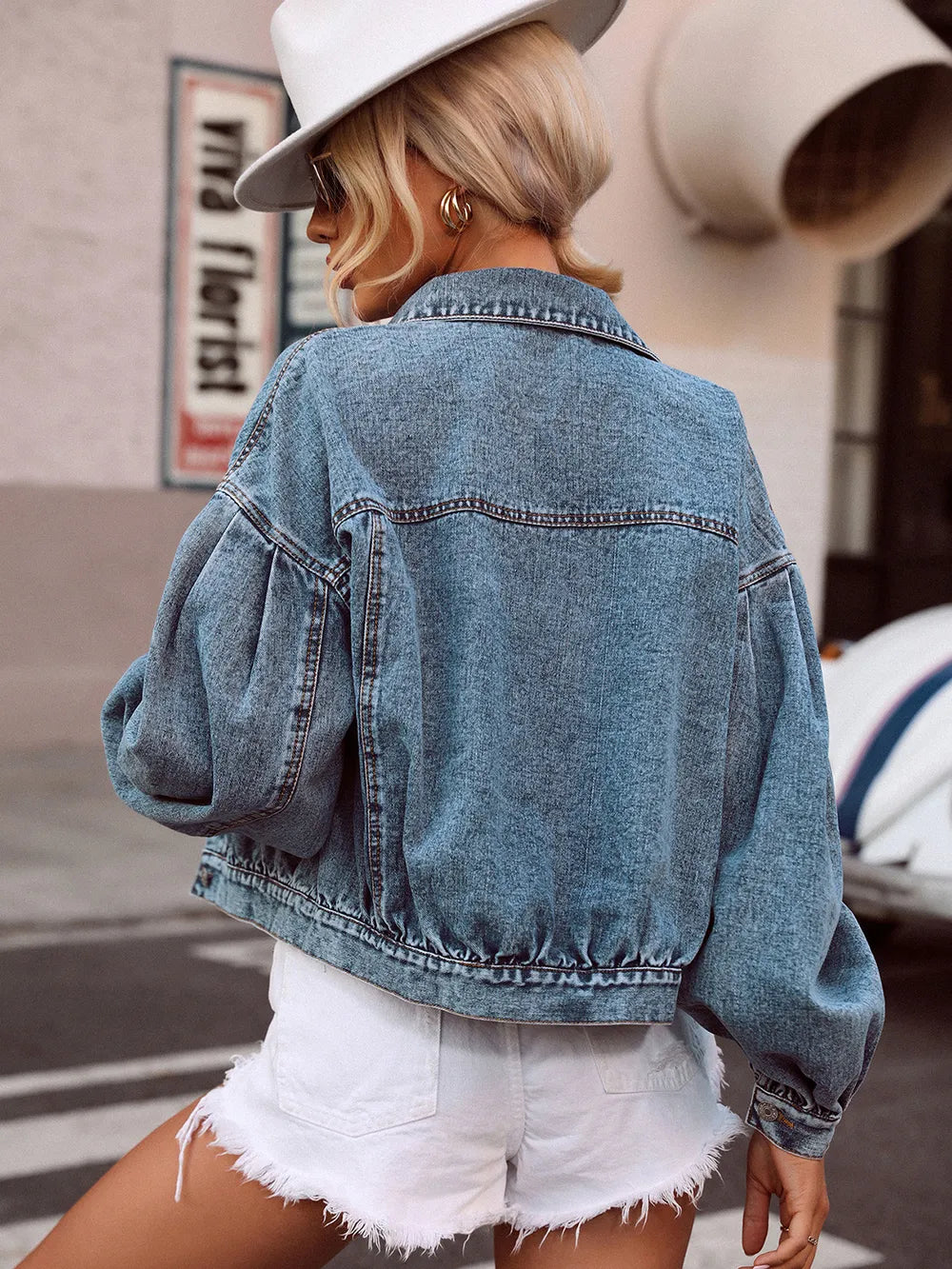 Person wearing a denim jacket and white shorts with a blurred background