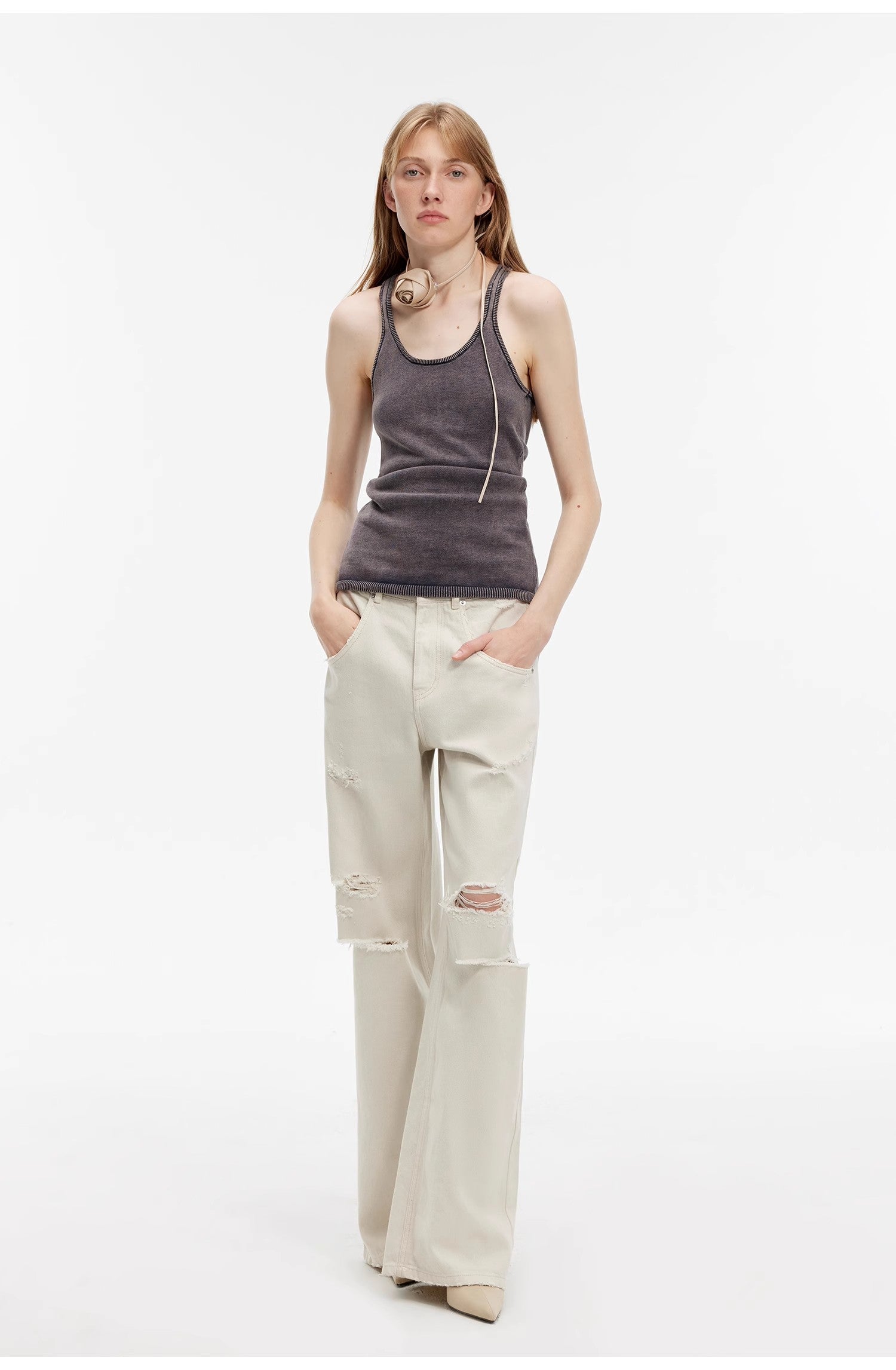 Person wearing a gray tank top and beige pants on a white background