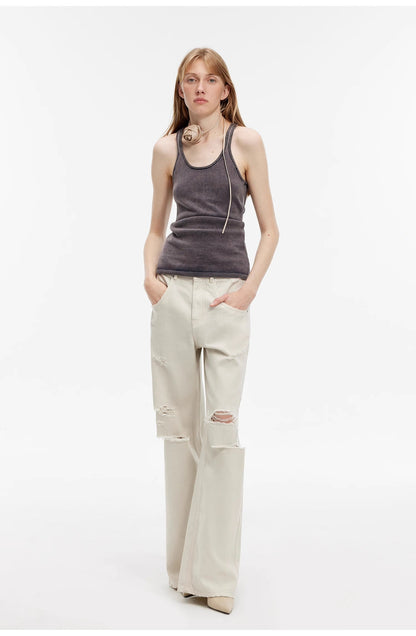 Person wearing a gray tank top and beige pants on a white background