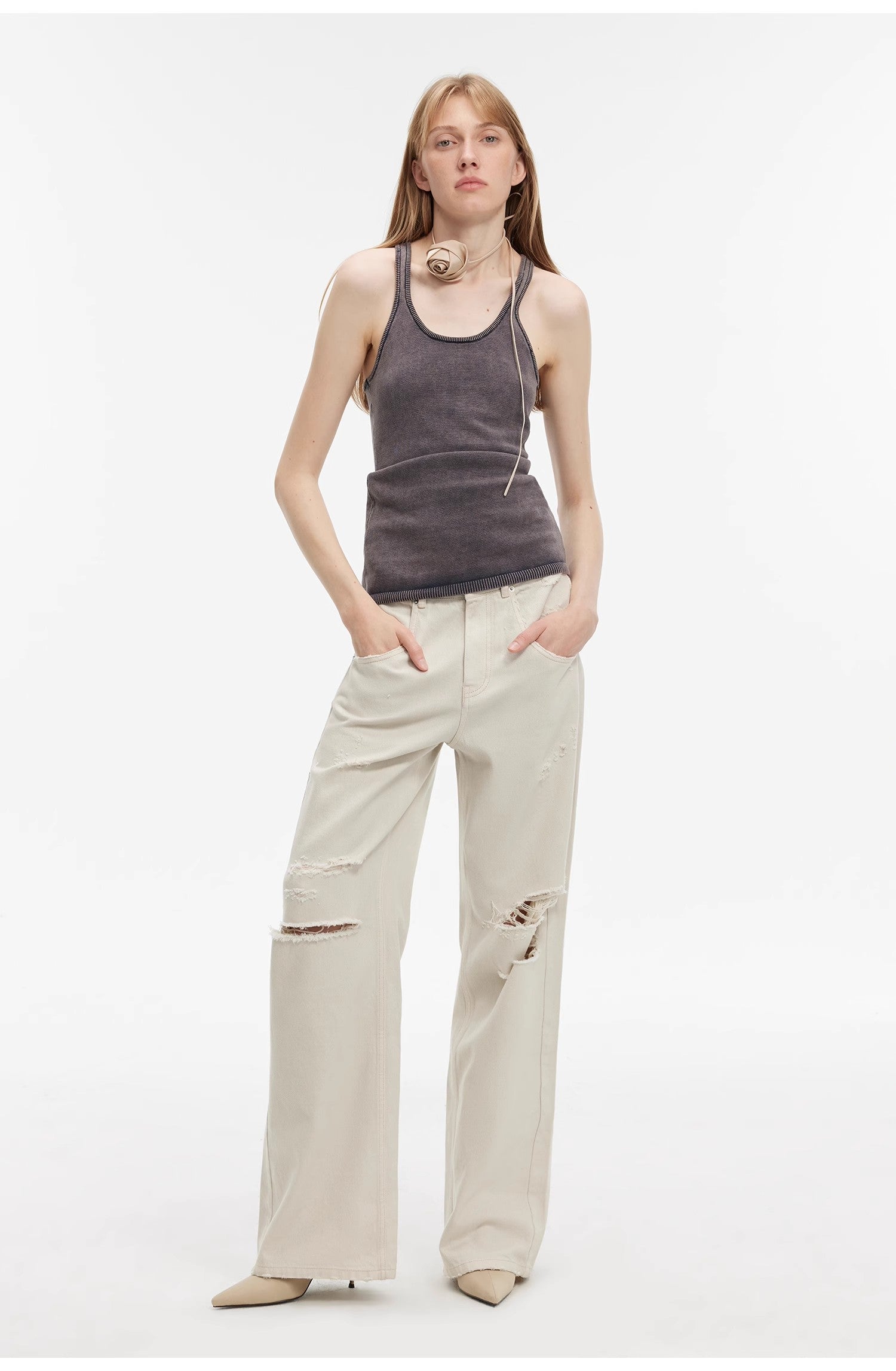 Woman wearing a gray tank top and beige pants on a white background
