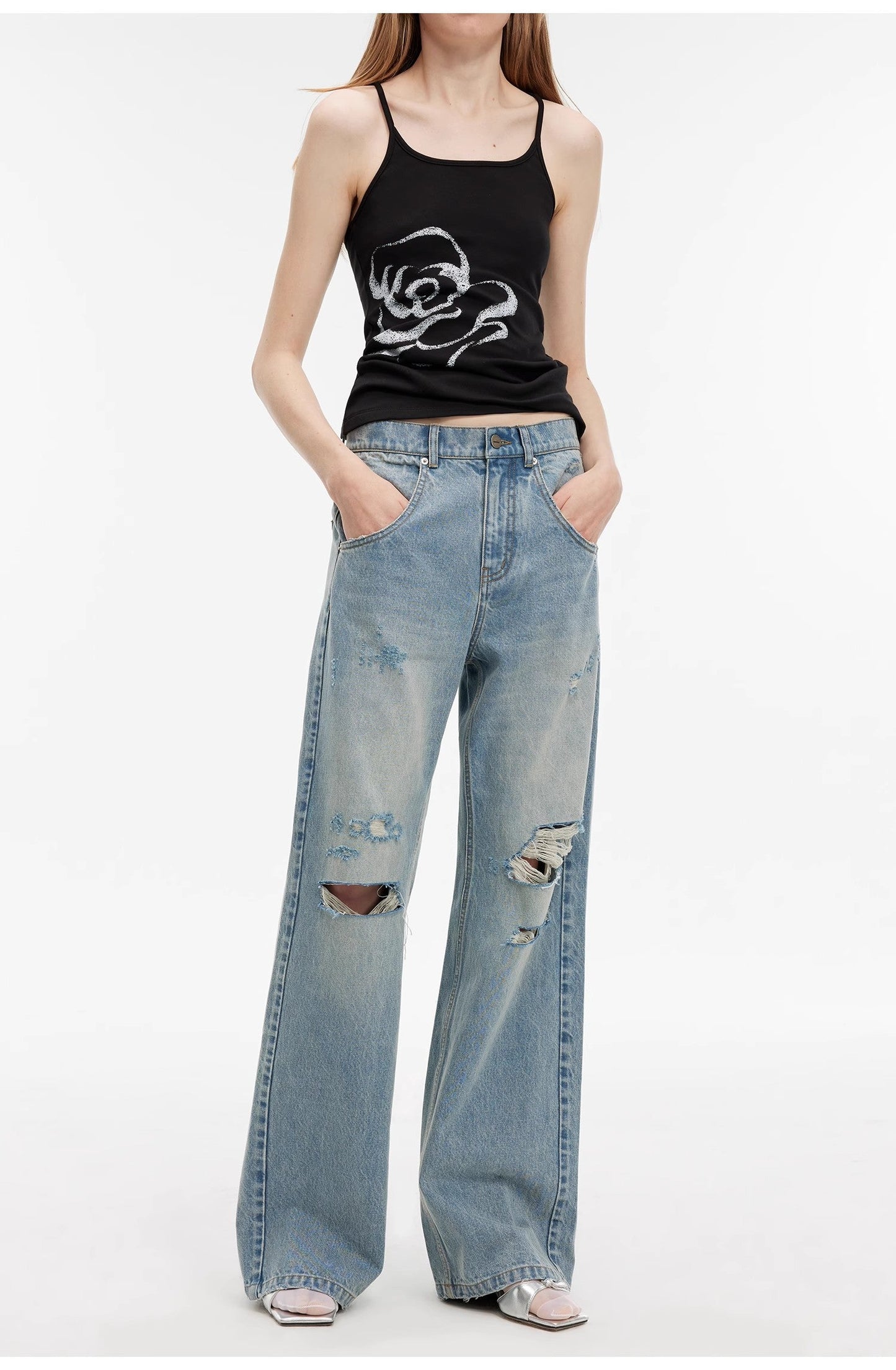 Person wearing a black tank top with a graphic design and light blue ripped jeans on a white background