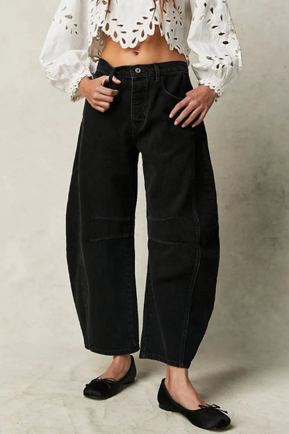 Person wearing a white blouse with black polka dots and black wide-leg pants on a neutral background