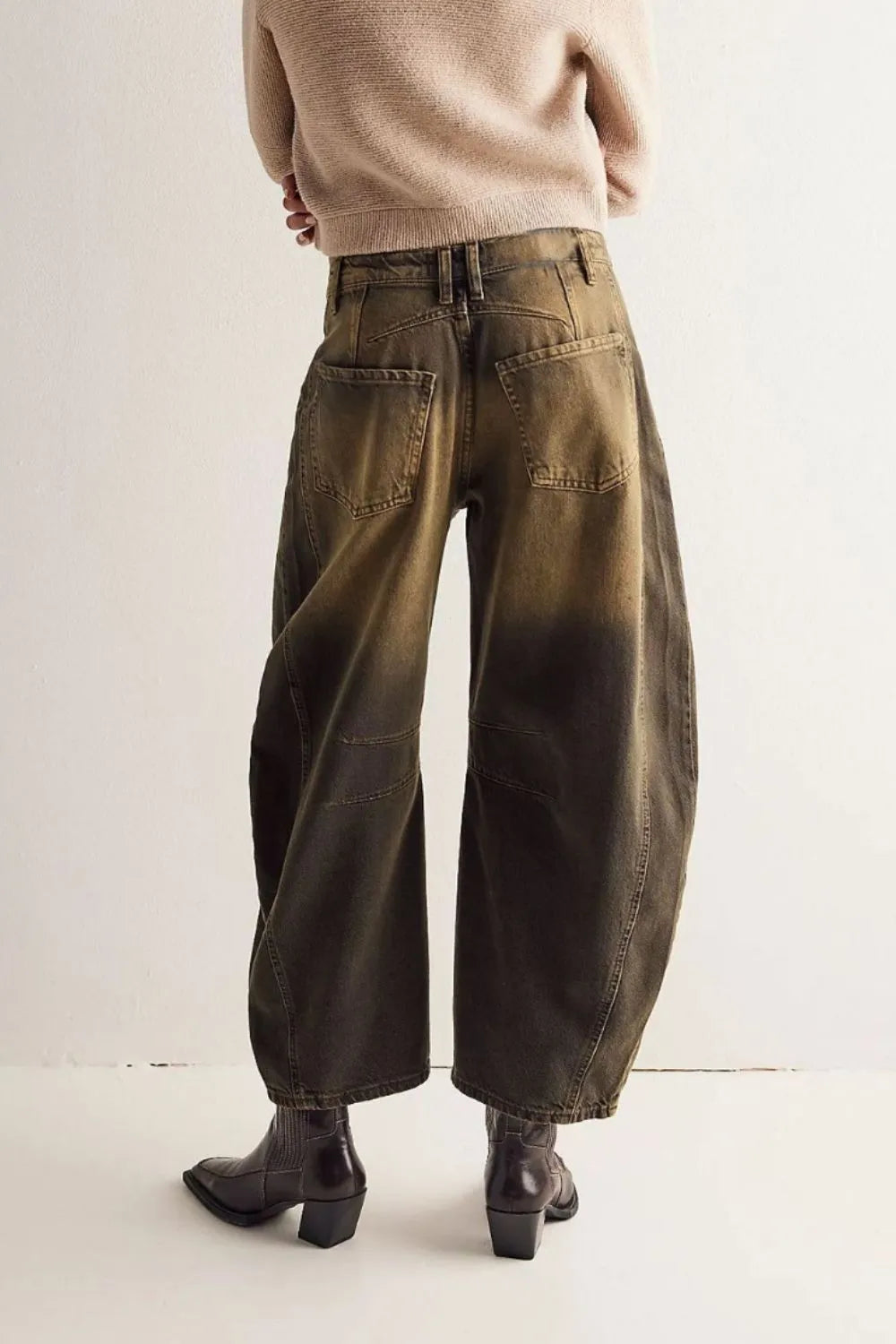 Person wearing wide-leg jeans and a beige sweater on a plain background