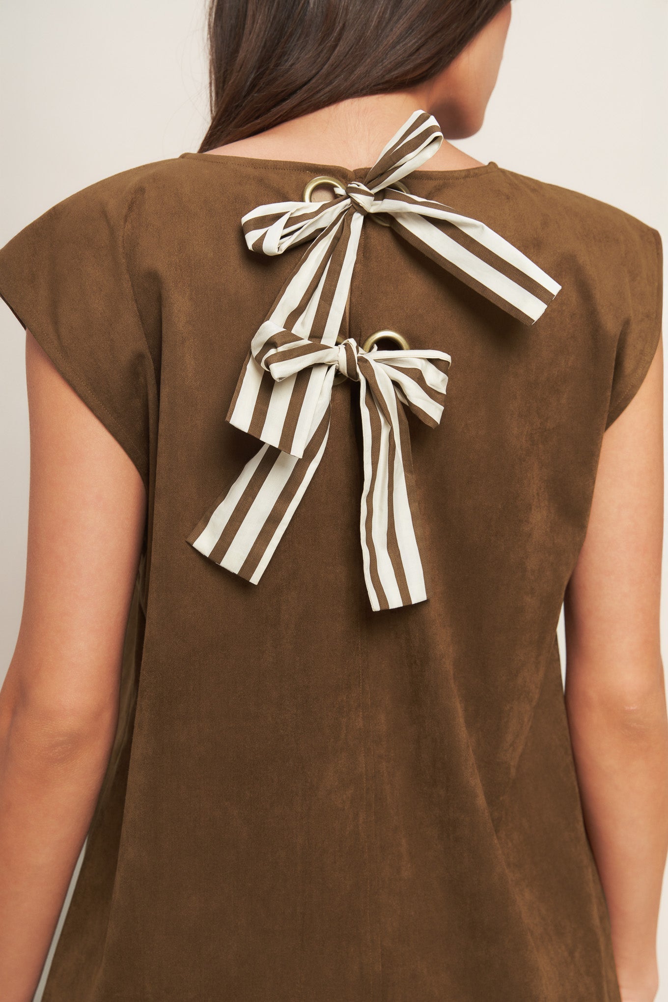 Brown top with striped bow detail on the back against a neutral background