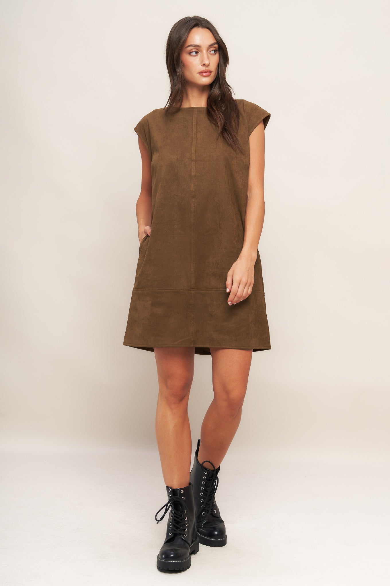 Woman wearing a brown dress with black boots on a white background