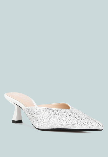 White pointed-toe mule with rhinestone embellishments on a light blue background