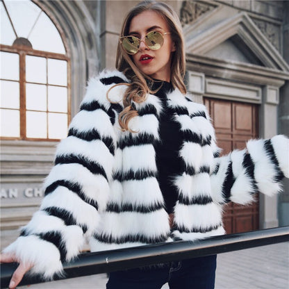 Woman wearing a black and white striped fur coat in front of a building.