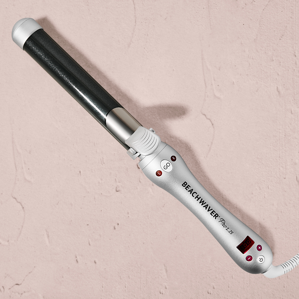 Silver and black Beachwaver curling iron on a beige background
