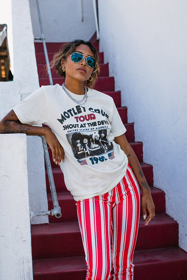 Person wearing a graphic t-shirt and red striped pants standing on red steps.
