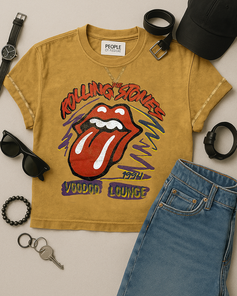 Yellow t-shirt with Rolling Stones logo, sunglasses, jeans, and accessories on a light background